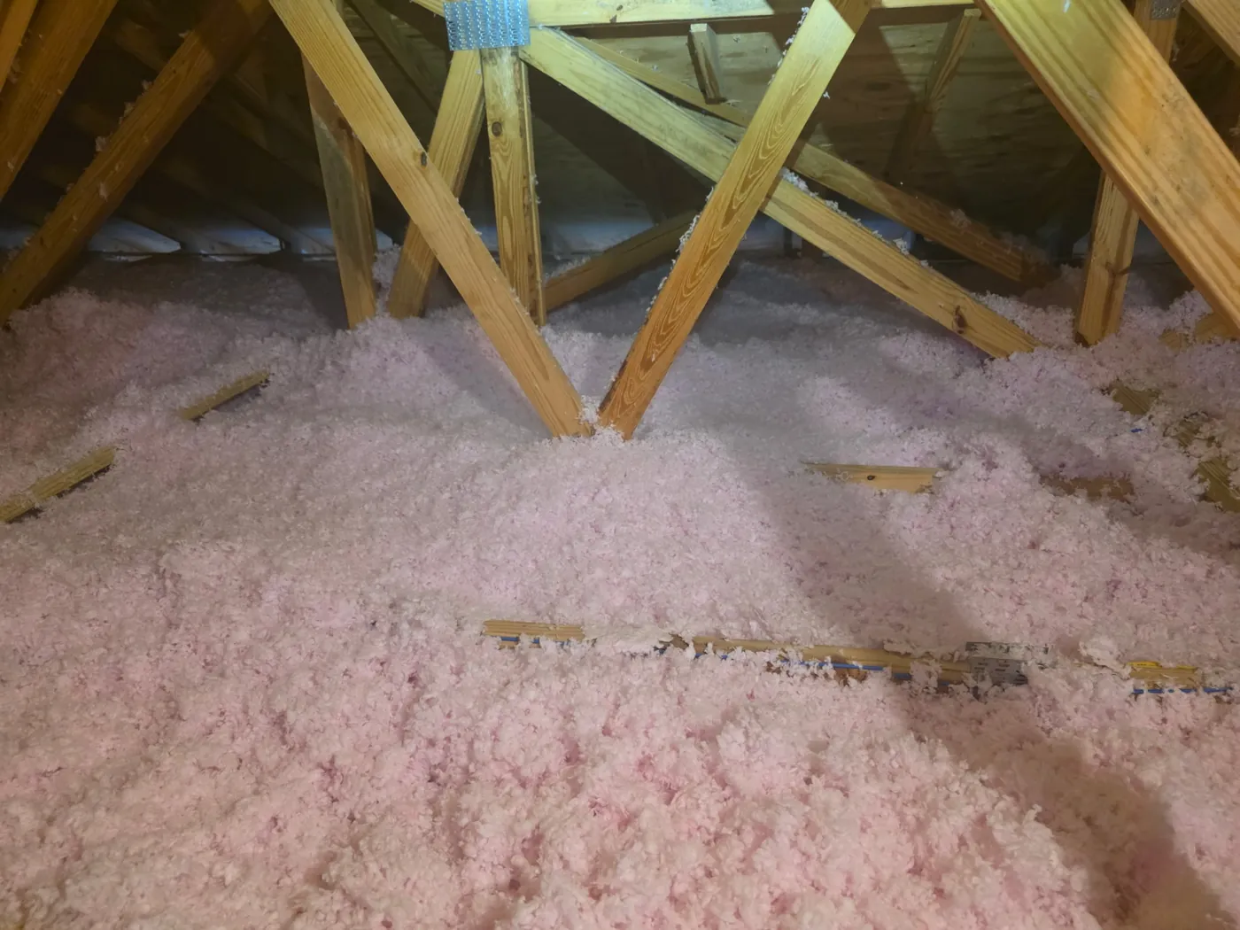 Deep blown-in insulation across an attic floor between roof trusses