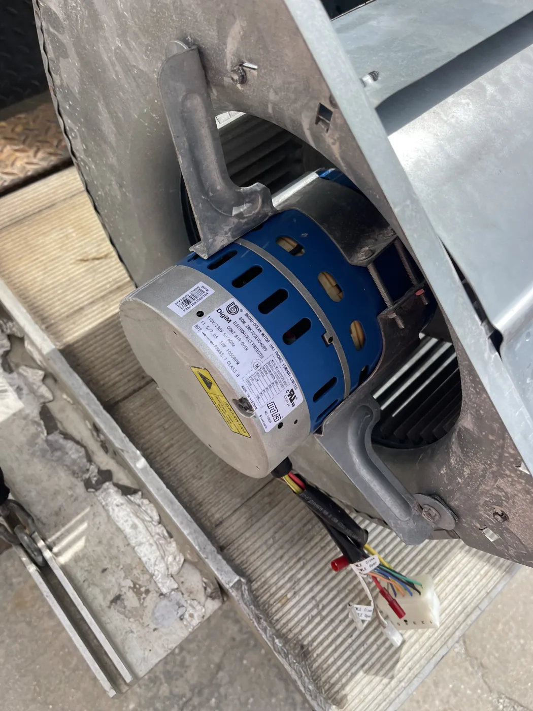 A blower motor seated in its housing during a replacement, wiring harness disconnected
