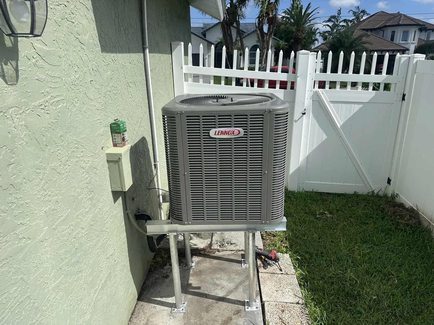 A new condenser mounted on an elevated aluminum stand beside a house
